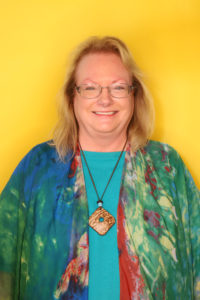 Dr. Carey Robertson, wearing a colorful shirt and smiling at the camera