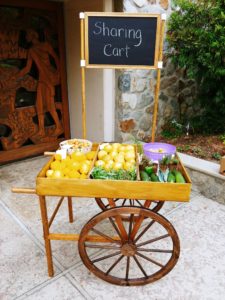 A wooden “Sharing Cart” filled with fresh produce.