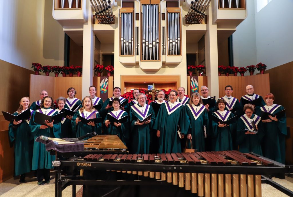 Members of the Chancel Choir wearing robes, singing, and smiling at the camera