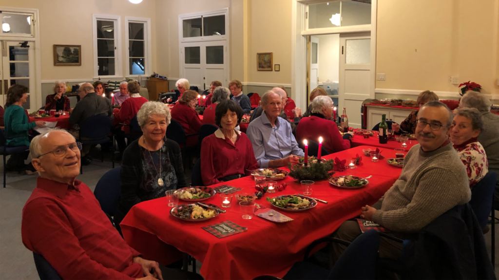A large group of older adults gathered at tables for a Christmas party