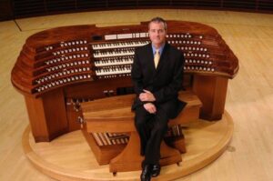 Organist Allan Morrison, sitting in front of an organ console.